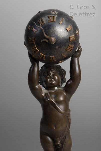 null Pendulette composé d’un angelot debout en bronze patiné soutenant un globe céleste...
