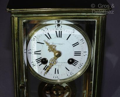 null Brass clock decorated with four bevelled glass panels, the white enamelled dial...