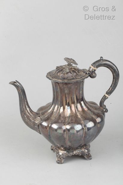 null A silver broad-rimmed coffee pot on a four-legged base with foliage and a flower...