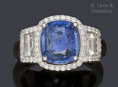 null A white gold ring set with a cushion sapphire and baguette diamonds surrounded...