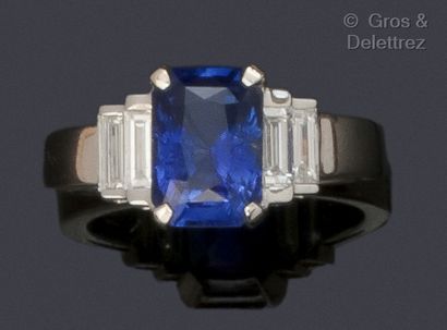 null A white gold ring set with a rectangular faceted sapphire and four baguette...