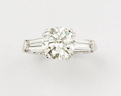 null Bague solitaire en or gris ornée d'un diamant taillé en brillant épaulé de deux...