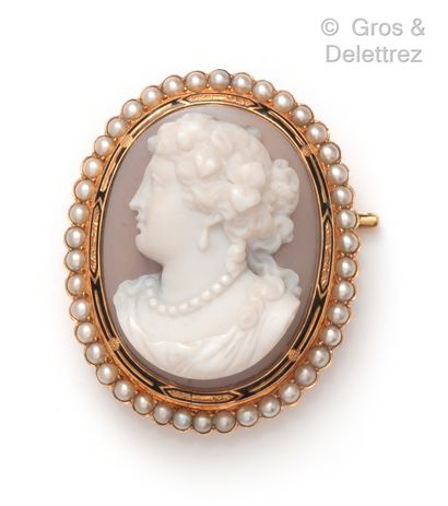  A yellow gold brooch with a cameo representing the profile of a woman in a half-pearl...