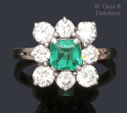 null White gold ring, set with a square emerald in a circle of brilliant-cut diamonds....