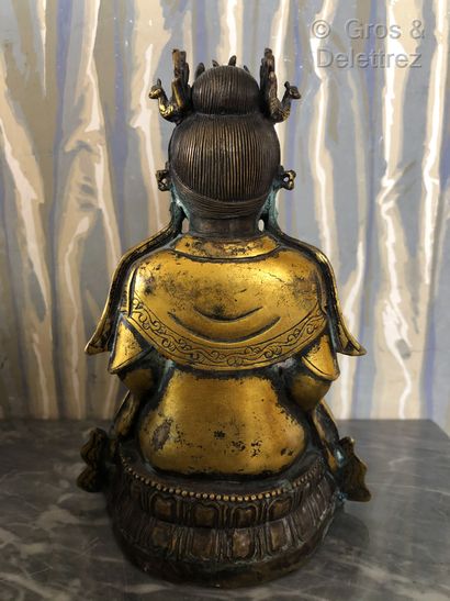 null Chine. Divinité bouddhique en bronze doré en position assis sur un socle godronné...