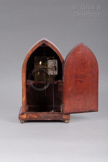 null An ogival clock in native wood veneer with inlaid decoration of nets and a rosette...