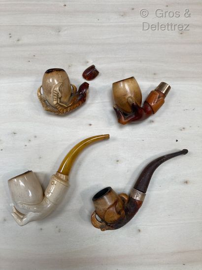  Lot of four carved meerschaum pipes featuring hands and talons holding the furnace,...