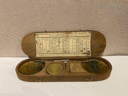 null Brass trebuchet scale in its oblong wooden travel case, with weights and indications.

Early...