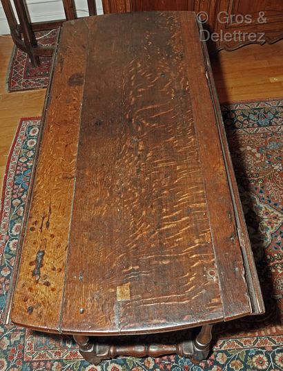  (Saint-Denis)Table ovale « getleg » en chêne patiné à volets abattants sur pieds...