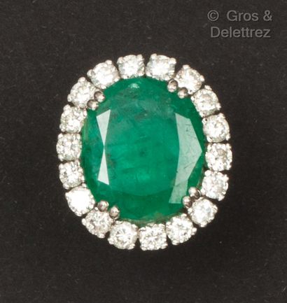 null A white gold ring, set with an oval emerald in a circle of brilliant-cut diamonds....