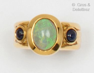 null A yellow gold ring with an opal cabochon and two sapphire cabochons. Finger...