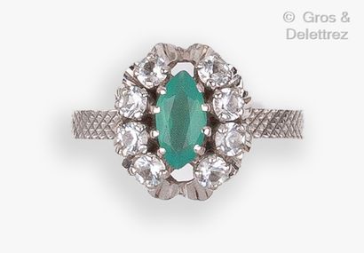 null A white gold ring set with a green navette stone and white stones. The ring...