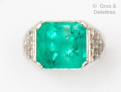  A white gold ring set with a rectangular emerald with triangular pavements set with...
