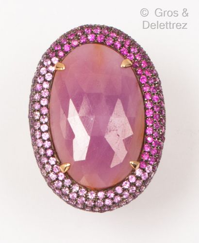 null A pink gold ring with a scroll design, set with an oval ruby root in a cameo...