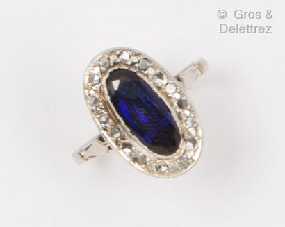 A white gold oval ring set with a blue stone...