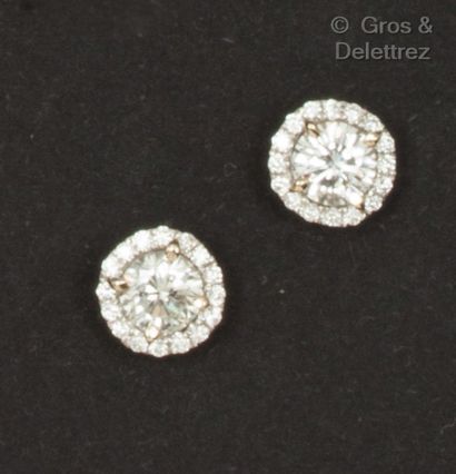 A pair of white gold earrings, each set with...