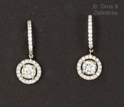 null A pair of white gold earrings, each set with a brilliant-cut diamond in a circle...