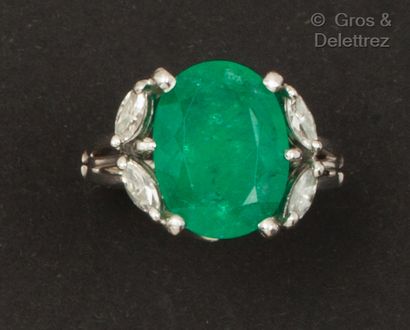 A white gold ring set with an oval emerald...