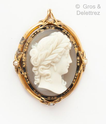 null A yellow gold brooch, partially enamelled and forming a frieze, holding a cameo...