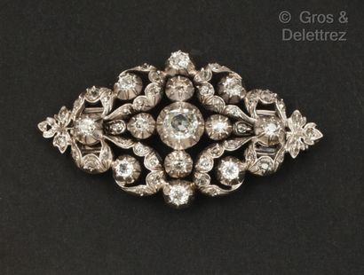 null A white gold and silver openwork brooch decorated with foliage and scrolls,...