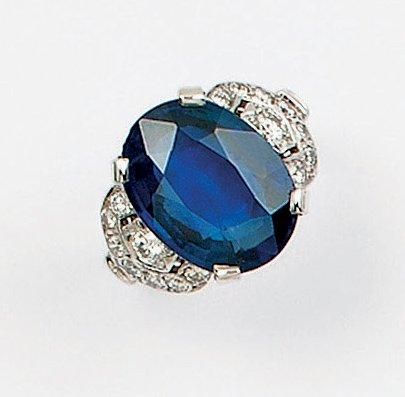 null Bague en or gris ornée d'un saphir ovale épaulé de diamants taillés en brillant....