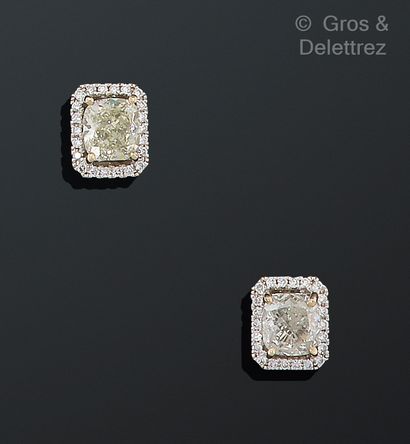 null Pair of white gold earrings, each with a cushion diamond in a setting of smaller...