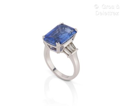 null White gold ring set with a rectangular sapphire and trapezoid diamonds. Finger...