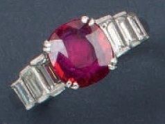 null Bague en or gris ornée d'un rubis taillé en coussin épaulé de diamants baguette....