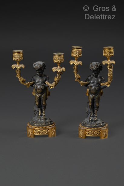 null Pair of ormolu and patinated candlesticks featuring two young fauns leaning...