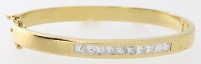  Bracelet rigide ouvrant en or jaune orné d'une ligne de diamants princesse. Poids...