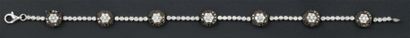 Edouard NAHUM Bracelet en or gris serti de diamants orné de sept motifs ronds sertis...