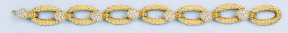 BOUCHERON : Bracelet articulé en or jaune guilloché ornée de sept motifs sertis de...