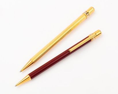 CARTIER Lot de deux stylos à bille en métal doré et émaillé. Signé Cartier.