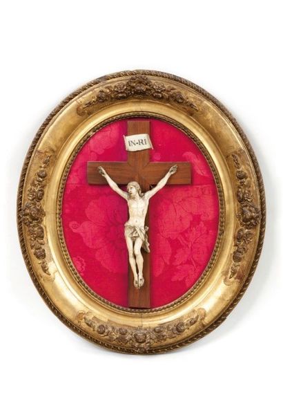 null Crucifix en ivoire dans un cadre ovale en bois et stuc doré à décor de fleurettes....