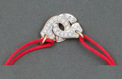 DINH VAN MENOTTES Bracelet sur cordon de soie rose ornée de deux motifs menottes...