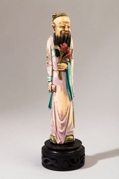 null Sujet en ivoire teinté polychrome représentant un sage debout tenant des fleurs...