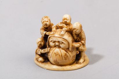 null Netsuke en ivoire représentant trois personnages sculptant une poupée Daruma....