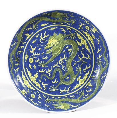 null Plat creux en porcelaine et émaux bleu et jaune à décor au centre d’un dragon...