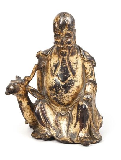 null Sujet en bronze laqué or représentant Zhoulao assis sur son daim. 
Chine, fin...