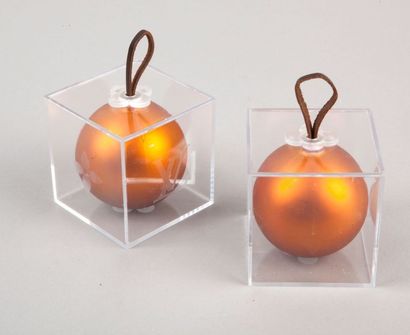 LOUIS VUITTON Lot de deux boules de noël orange dans des cubes en plexiglas.