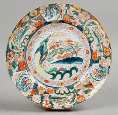 CHINE Plat rond à bord uni à décor polychrome dans la palette Imari d'un paysage...