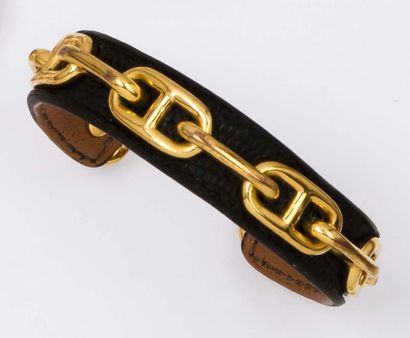HERMES Bracelet jonc ouvert en métal doré à décor de chaine d'ancre sur cuir.
Signé...