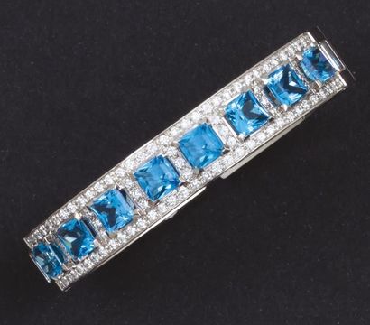 null Bracelet rigide ouvrant en or gris ajouré orné de huit topazes bleues bordées...