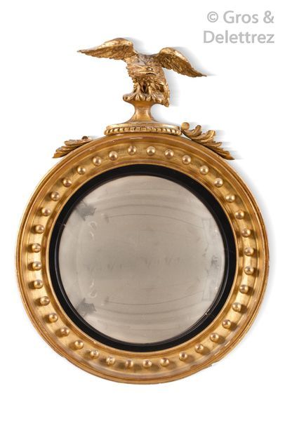 null Miroir ovale en bois sculpté et doré à décor de boules, surmontée d’un aigle...