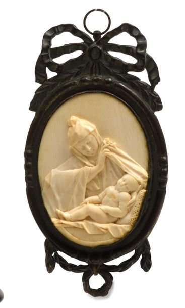 null PLAQUE VOTIVE en ivoire sculpté figurant une Vierge à l’enfant.. Dans un encadrement...