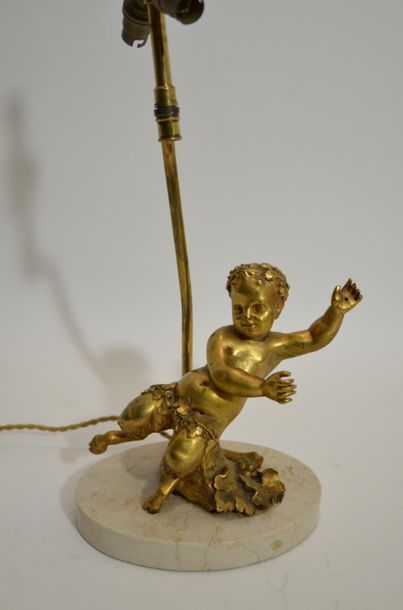 null LAMPE en bronze doré à décor de "pan" enfant sur un socle ovale en marbre beige....