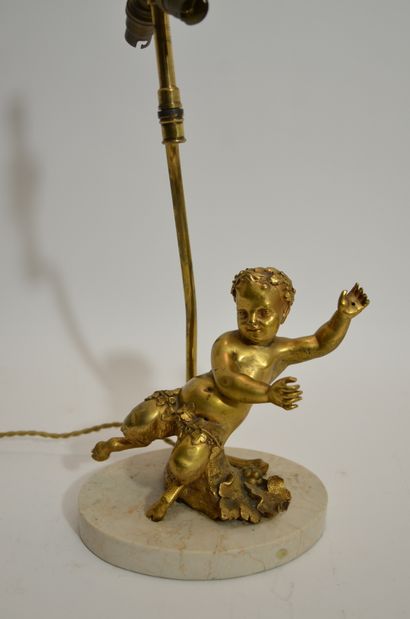 null A gilt bronze LAMP decorated with a child "pan" on an oval beige marble base....