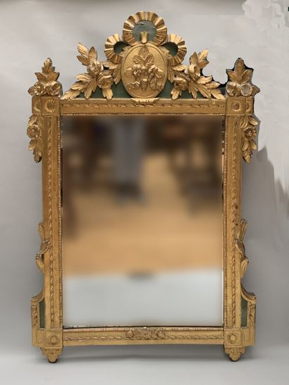 null Carved and gilded wood mirror decorated with pearl friezes and foliage, topped...