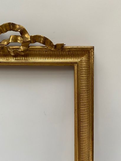 null A carved and gilded wood frame, the pediment centered with an openwork ribbon...