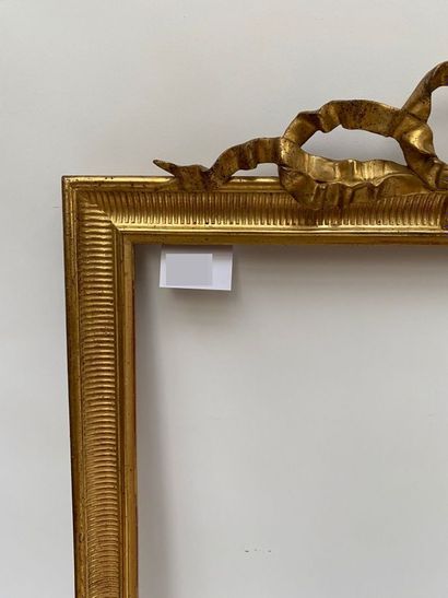 null A carved and gilded wood frame, the pediment centered with an openwork ribbon...